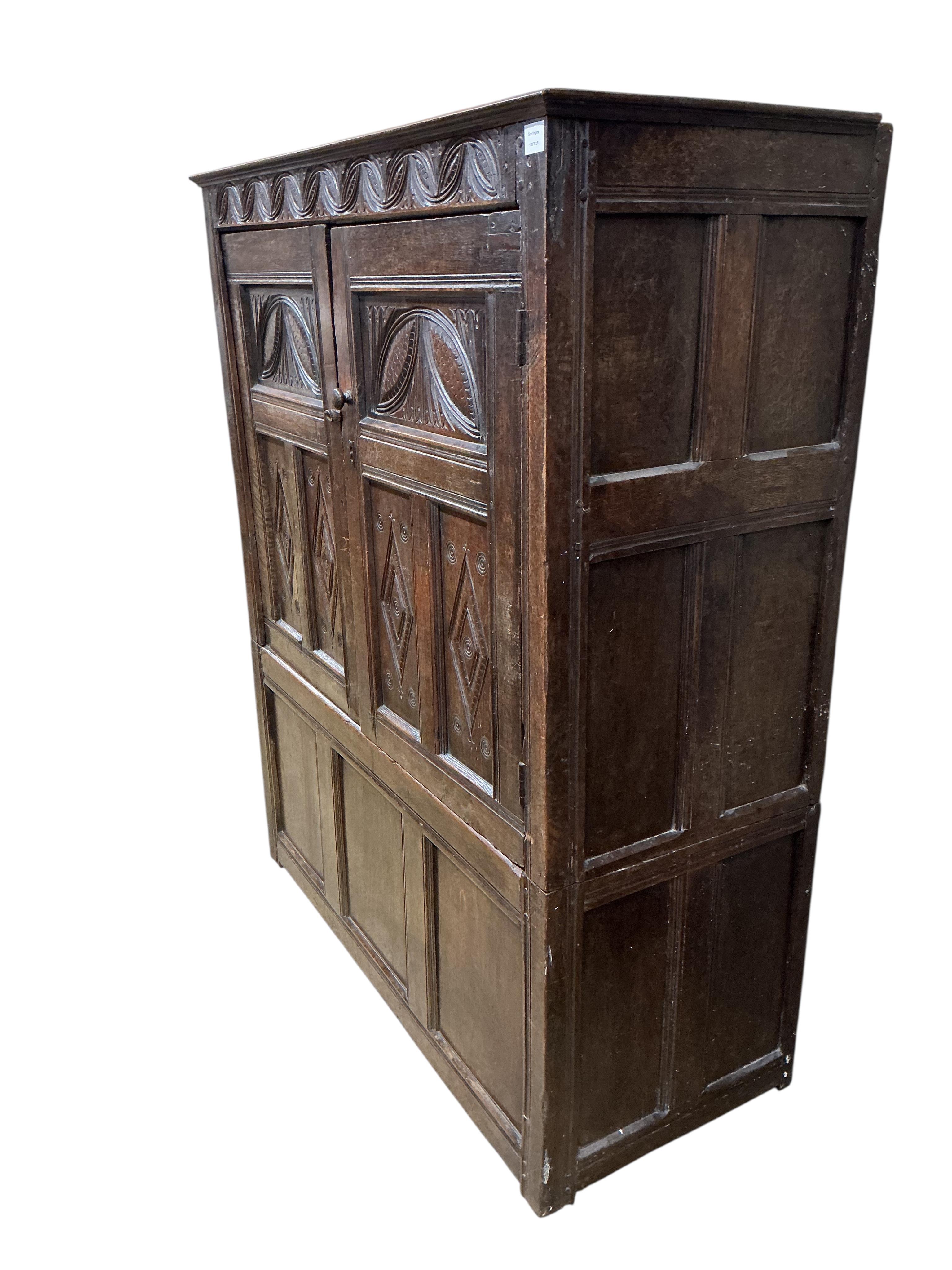 An early 18th century carved oak hanging cupboard, width 133cm, depth 56cm, height 162cm